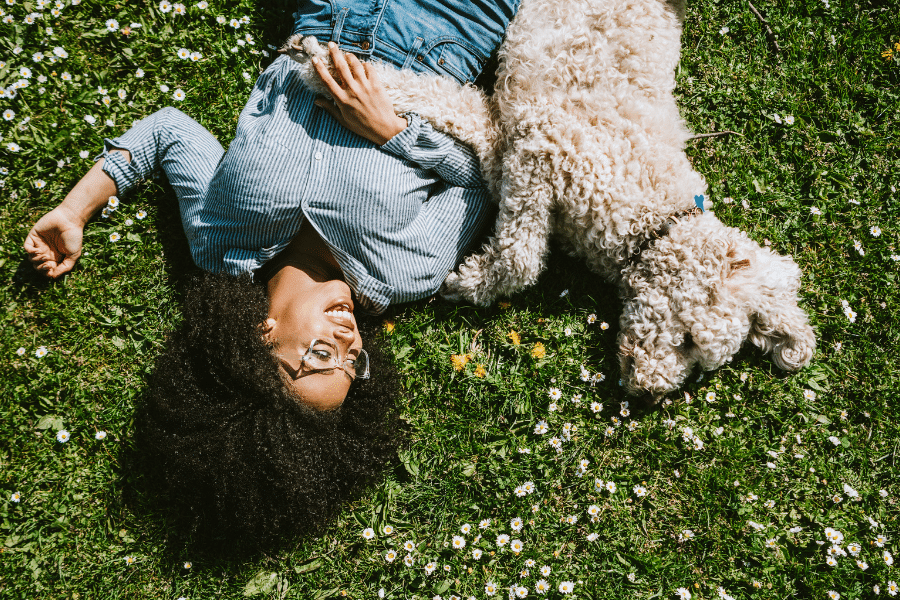 Personne allongée sur de l'herbe avec chien.